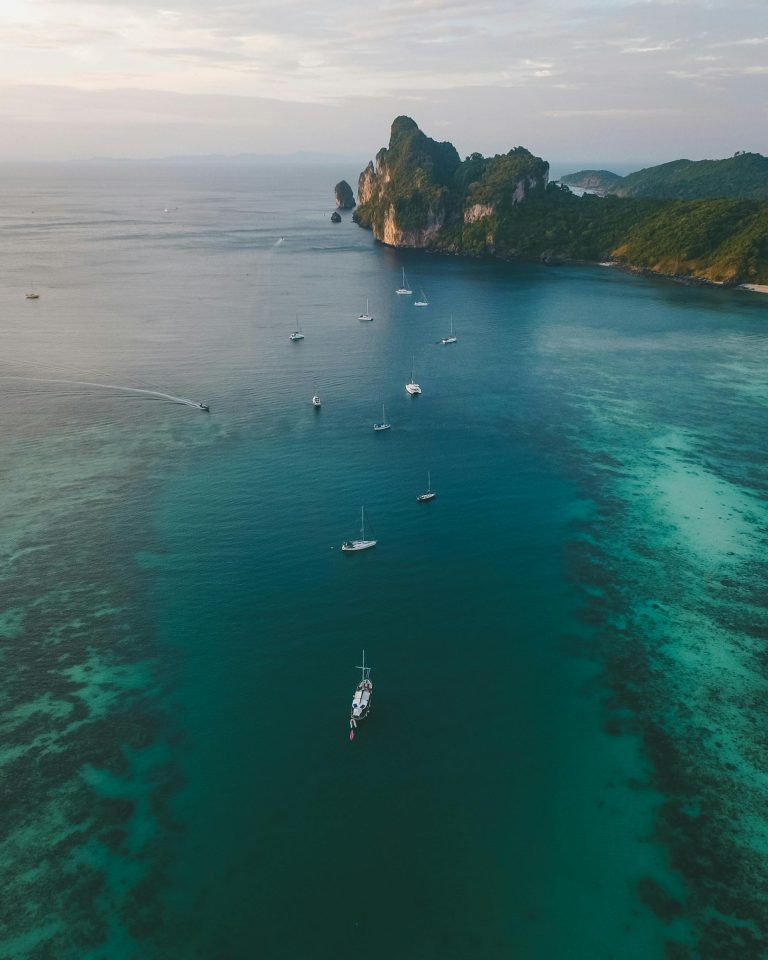 Breathtaking aerial view of Ao Nang Bay in Thailand, showcasing serene waters and sailboats.