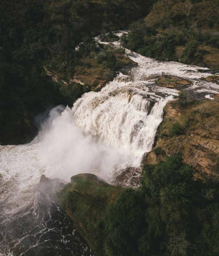 A breathtaking aerial view of a powerful waterfall cascading through a verdant forest.